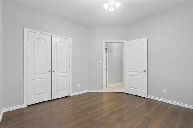 unfurnished bedroom with wood finished floors, baseboards, and a closet