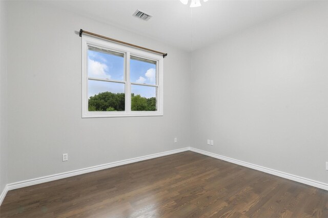 spare room featuring dark wood-type flooring and baseboards