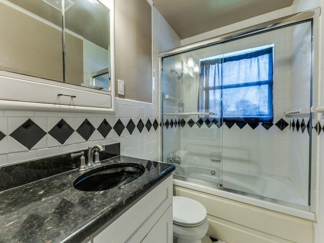 13134 Ravenview Rd, Dallas, TX 75253 - full bathroom featuring tile walls, vanity, enclosed tub / shower combo, toilet, and a textured wall