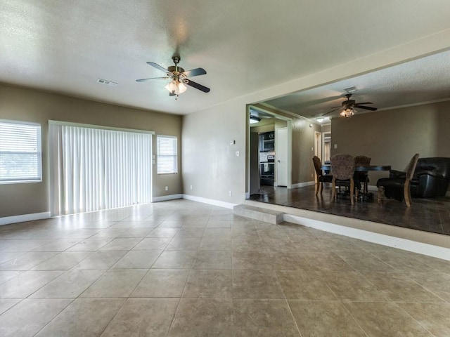 13134 Ravenview Rd, Dallas, TX 75253 - living area featuring ceiling fan, tile patterned flooring, baseboards, and a textured ceiling