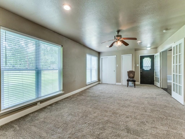 13134 Ravenview Rd, Dallas, TX 75253 - unfurnished living room featuring ceiling fan, carpet, healthy amount of natural light, a textured ceiling, and baseboards