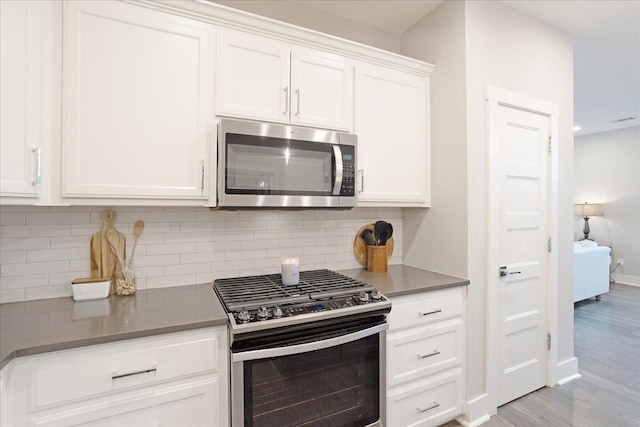 kitchen featuring appliances with stainless steel finishes, backsplash, white cabinets, light wood finished floors, and recessed lighting