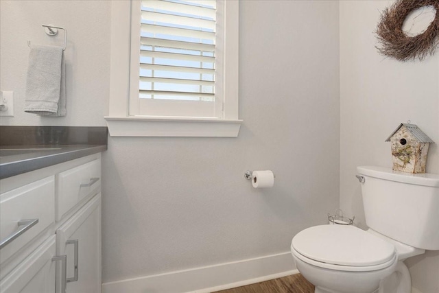 bathroom with vanity, toilet, baseboards, and wood finished floors