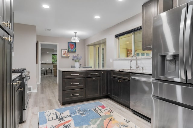 3809 Runge Ct E, Irving, TX 75038 - kitchen with stainless steel appliances, a sink, a peninsula, light wood-type flooring, and light stone counters