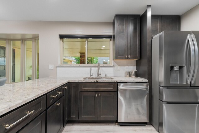 3809 Runge Ct E, Irving, TX 75038 - kitchen with appliances with stainless steel finishes, a sink, light stone countertops, backsplash, and light wood finished floors