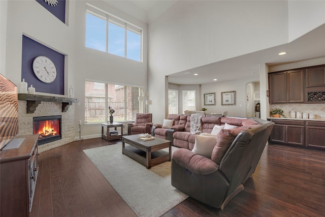 4458 Hartebeest Trl, Frisco, TX 75034 - living room with a fireplace, a high ceiling, dark wood-type flooring, arched walkways, and recessed lighting