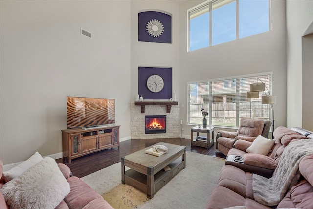 4458 Hartebeest Trl, Frisco, TX 75034 - living room featuring a towering ceiling, a stone fireplace, healthy amount of natural light, baseboards, and wood finished floors