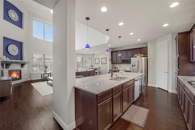 4458 Hartebeest Trl, Frisco, TX 75034 - kitchen with a sink, open floor plan, stainless steel appliances, dark wood-style flooring, and a stone fireplace