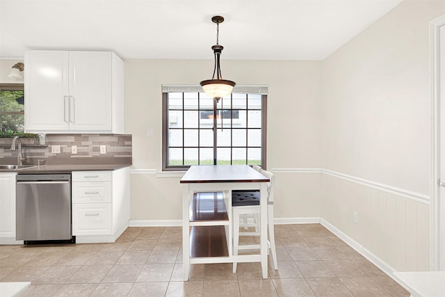 kitchen featuring stainless steel dishwasher, plenty of natural light, decorative backsplash, and white cabinetry