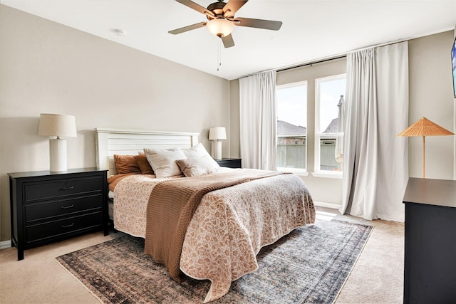 bedroom featuring light colored carpet, a ceiling fan, and baseboards