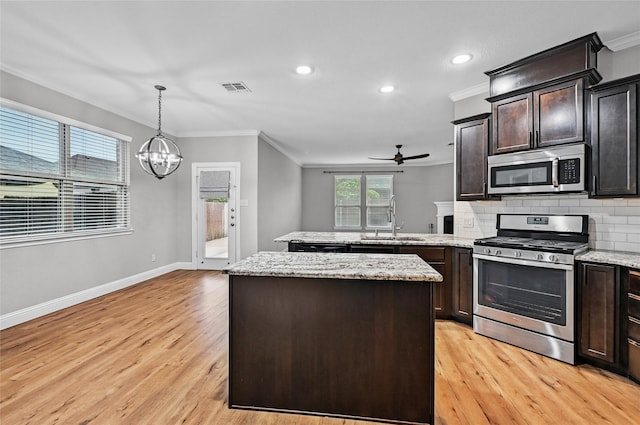kitchen featuring stainless steel appliances, a sink, crown molding, a peninsula, and a ceiling fan