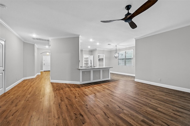 unfurnished living room with ceiling fan, wood finished floors, ornamental molding, baseboards, and recessed lighting