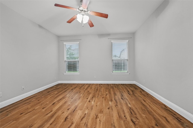 spare room featuring baseboards, wood finished floors, and a ceiling fan