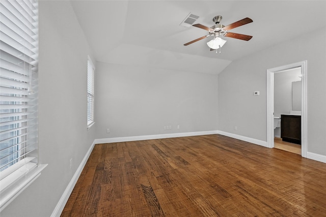 unfurnished bedroom featuring lofted ceiling, wood finished floors, baseboards, ensuite bathroom, and ceiling fan