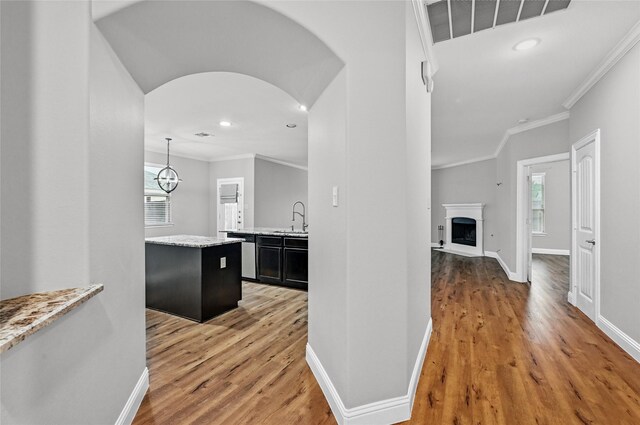 corridor with a sink, light wood-style flooring, ornamental molding, baseboards, and recessed lighting