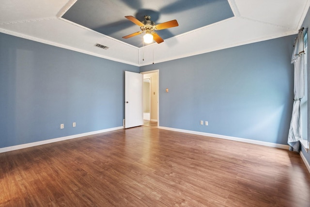 spare room with a tray ceiling, a ceiling fan, wood finished floors, and baseboards