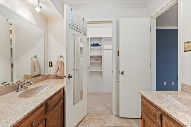 bathroom with two vanities, tile patterned flooring, and a walk in closet