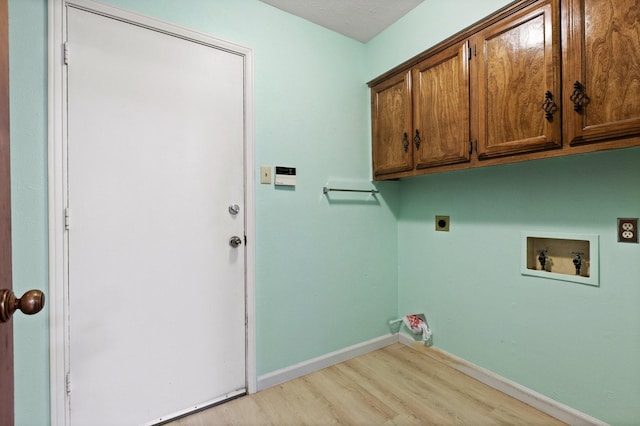washroom featuring hookup for an electric dryer, hookup for a washing machine, light wood-type flooring, cabinet space, and baseboards