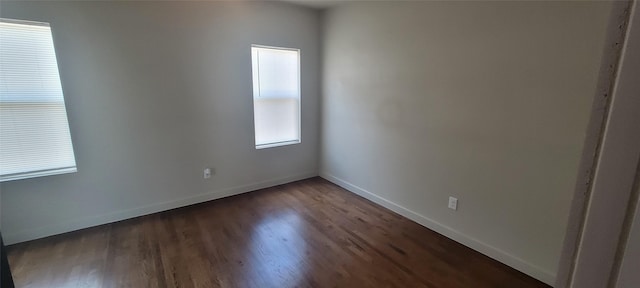 unfurnished room with dark wood-type flooring and baseboards
