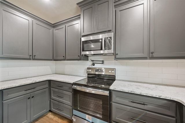 2735 S Jennings Ave, Fort Worth, TX 76110 - kitchen with appliances with stainless steel finishes, gray cabinetry, and decorative backsplash