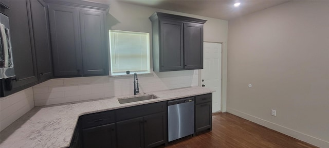 kitchen with stainless steel dishwasher, a sink, tasteful backsplash, dark wood-style floors, and baseboards