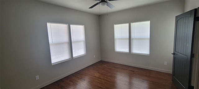 spare room featuring a ceiling fan, dark wood-style flooring, and baseboards