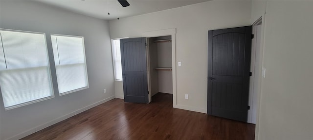 unfurnished bedroom with wood finished floors, a closet, baseboards, and a spacious closet