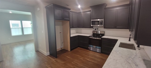 kitchen with stainless steel appliances, light stone countertops, backsplash, dark wood-style flooring, and baseboards