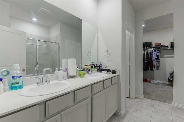 full bath featuring a shower stall, double vanity, a walk in closet, and tile patterned flooring