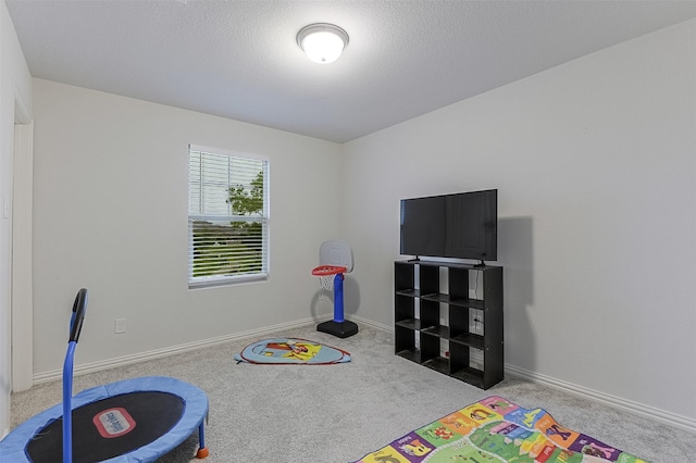 playroom featuring carpet floors, baseboards, and a textured ceiling