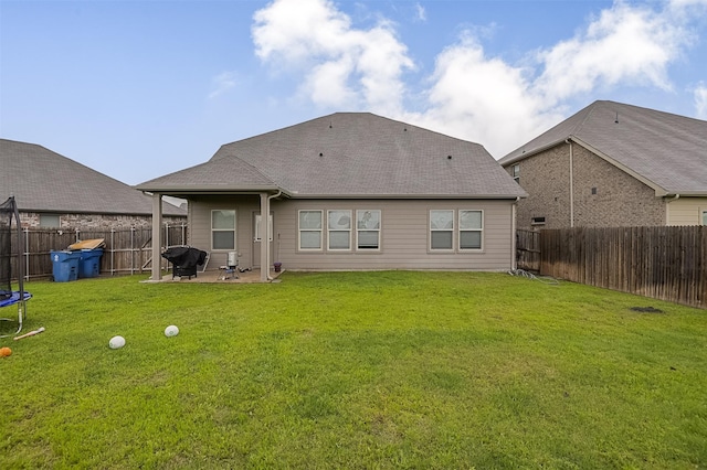 back of house featuring a patio, a trampoline, and roof with shingles