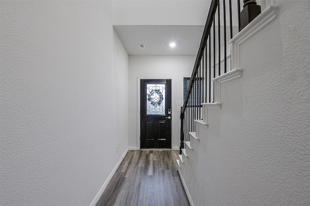 entryway with a textured wall, dark wood-type flooring, baseboards, stairs, and recessed lighting