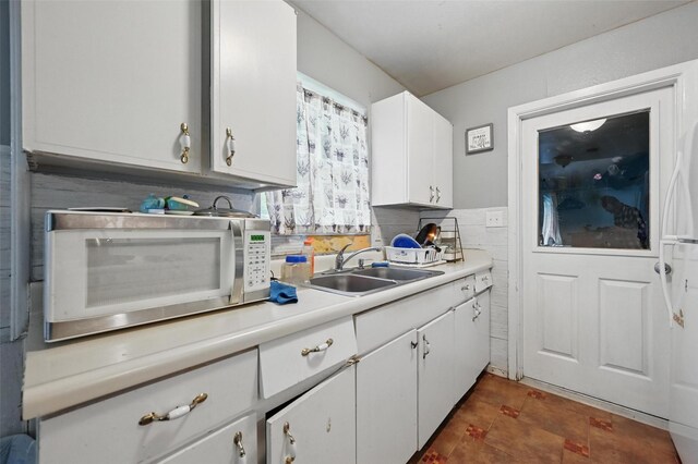 kitchen with light countertops, a sink, and white cabinetry