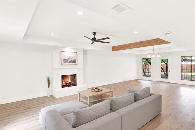 303 Randy Lee Ln, Mckinney, TX 75071 - living room featuring recessed lighting, baseboards, light wood finished floors, a warm lit fireplace, and a raised ceiling