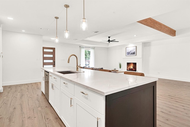 303 Randy Lee Ln, Mckinney, TX 75071 - kitchen featuring a sink, light wood-style flooring, a lit fireplace, ceiling fan, and white cabinetry