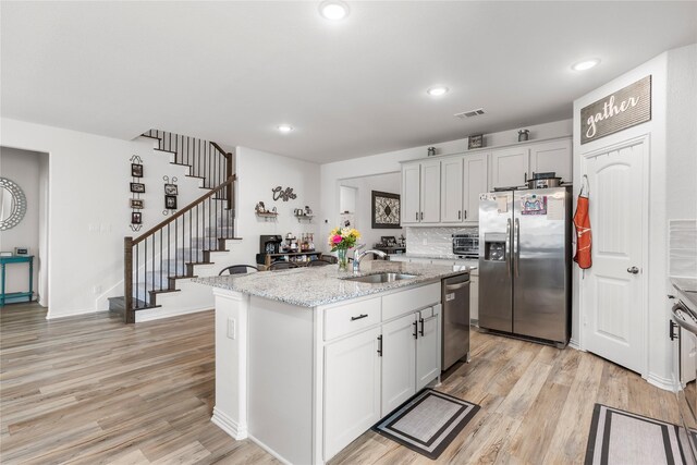 804 Feather Edge Dr, Springtown, TX 76082 - kitchen featuring stainless steel appliances, a sink, light wood finished floors, light stone counters, and a kitchen island with sink
