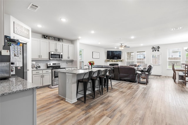 804 Feather Edge Dr, Springtown, TX 76082 - kitchen with appliances with stainless steel finishes, light wood finished floors, a ceiling fan, a breakfast bar area, and open floor plan