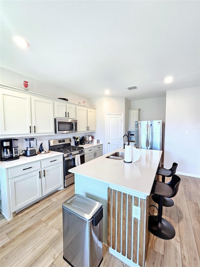 3405 Western Trl, Crandall, TX 75114 - kitchen featuring stainless steel appliances, a sink, a kitchen bar, a center island with sink, and light wood-style flooring