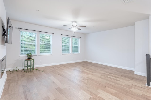 spare room featuring a ceiling fan, light wood-style flooring, and baseboards