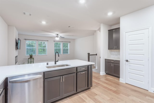 kitchen with stainless steel dishwasher, a sink, light wood-style flooring, light countertops, and recessed lighting