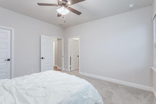 bedroom with light colored carpet, baseboards, and a ceiling fan