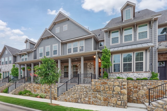 craftsman inspired home with stairway, stone siding, covered porch, and a shingled roof