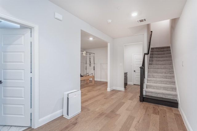 staircase featuring wood finished floors, baseboards, and recessed lighting