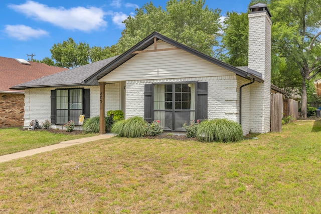 ranch-style house featuring brick siding, a chimney, and roof with shingles