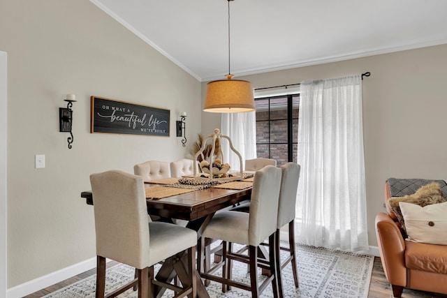dining space with light wood-style floors, ornamental molding, baseboards, and lofted ceiling