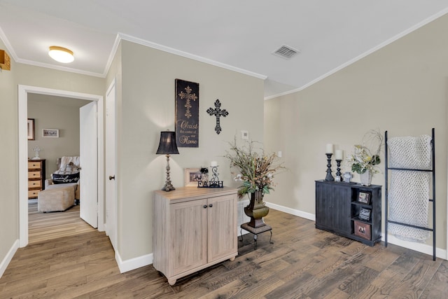 hall featuring wood finished floors, baseboards, and ornamental molding