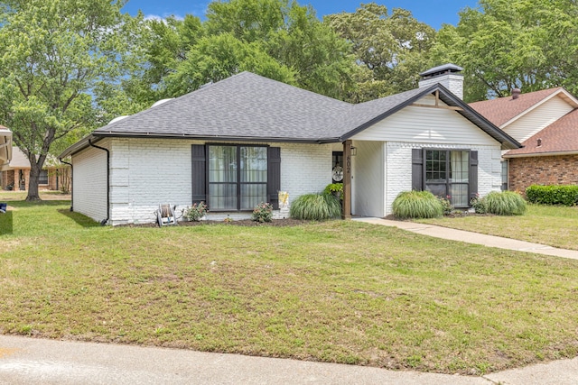 ranch-style home with brick siding, a shingled roof, a front yard, and a chimney