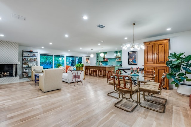 dining space featuring a fireplace, recessed lighting, and light wood-style floors