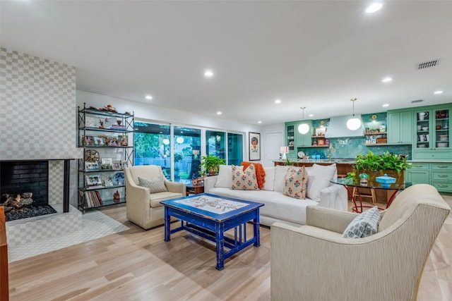 living area featuring light wood finished floors, recessed lighting, wallpapered walls, and a tile fireplace