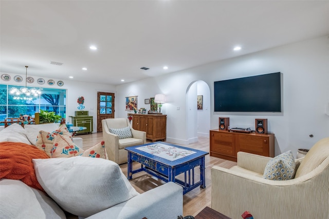 living room featuring arched walkways, recessed lighting, and light wood-style floors